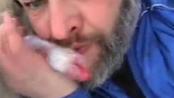 Dude with a beard licking a dog's dick outdoors